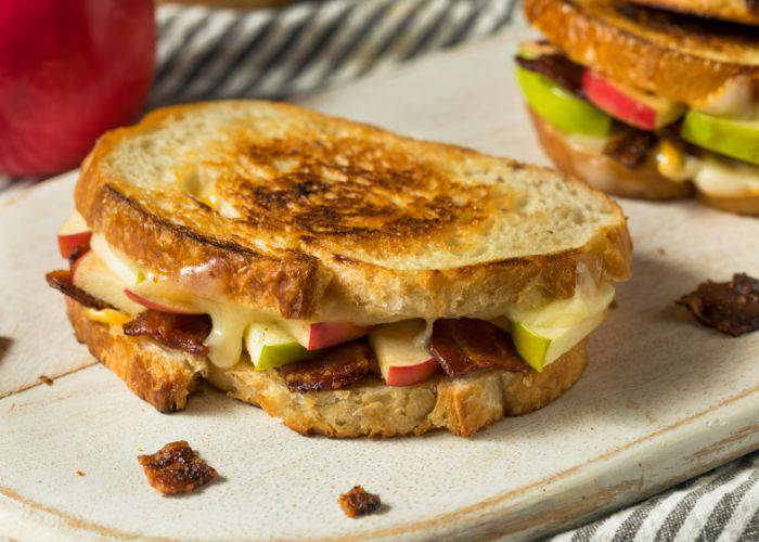 A grilled sandwich filled with apple, bacon and cheese.